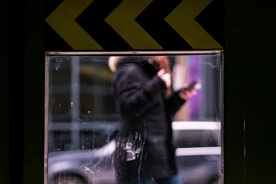 reflection of person looking at phone while walking