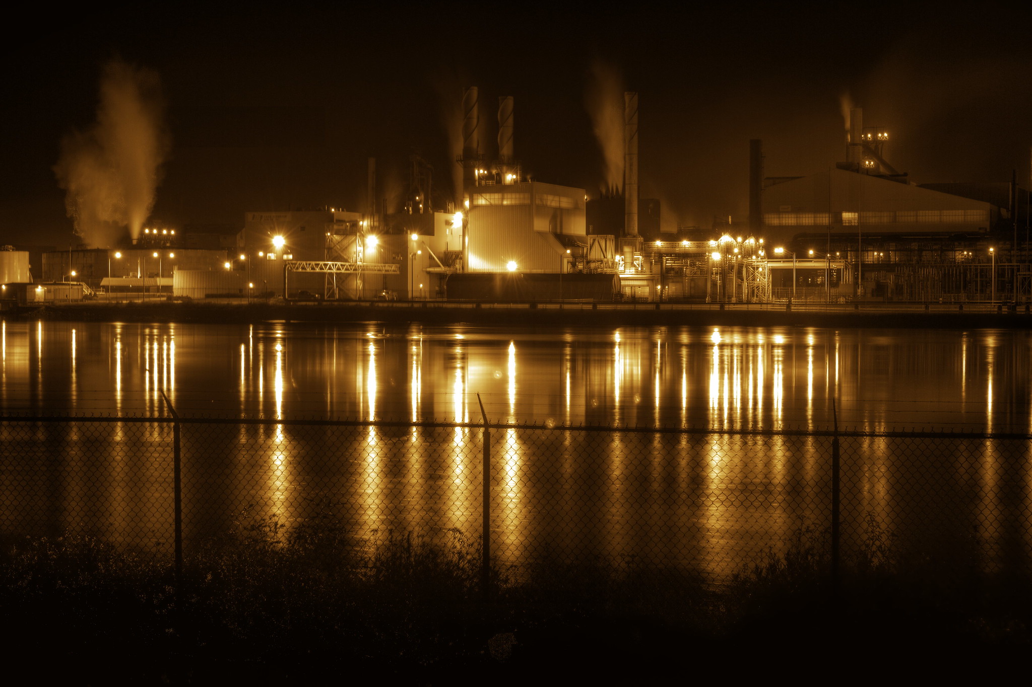 Essar Steel mill in Ontario, taking at night. A manufacturing plant lit up at night, seen from across a river.