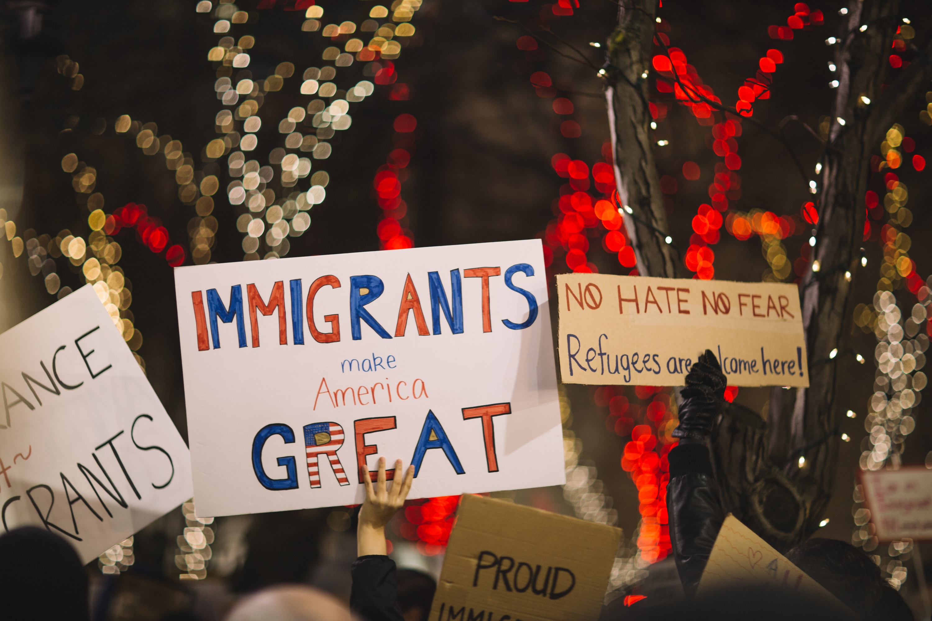 people holding signs that support immigration and refugees