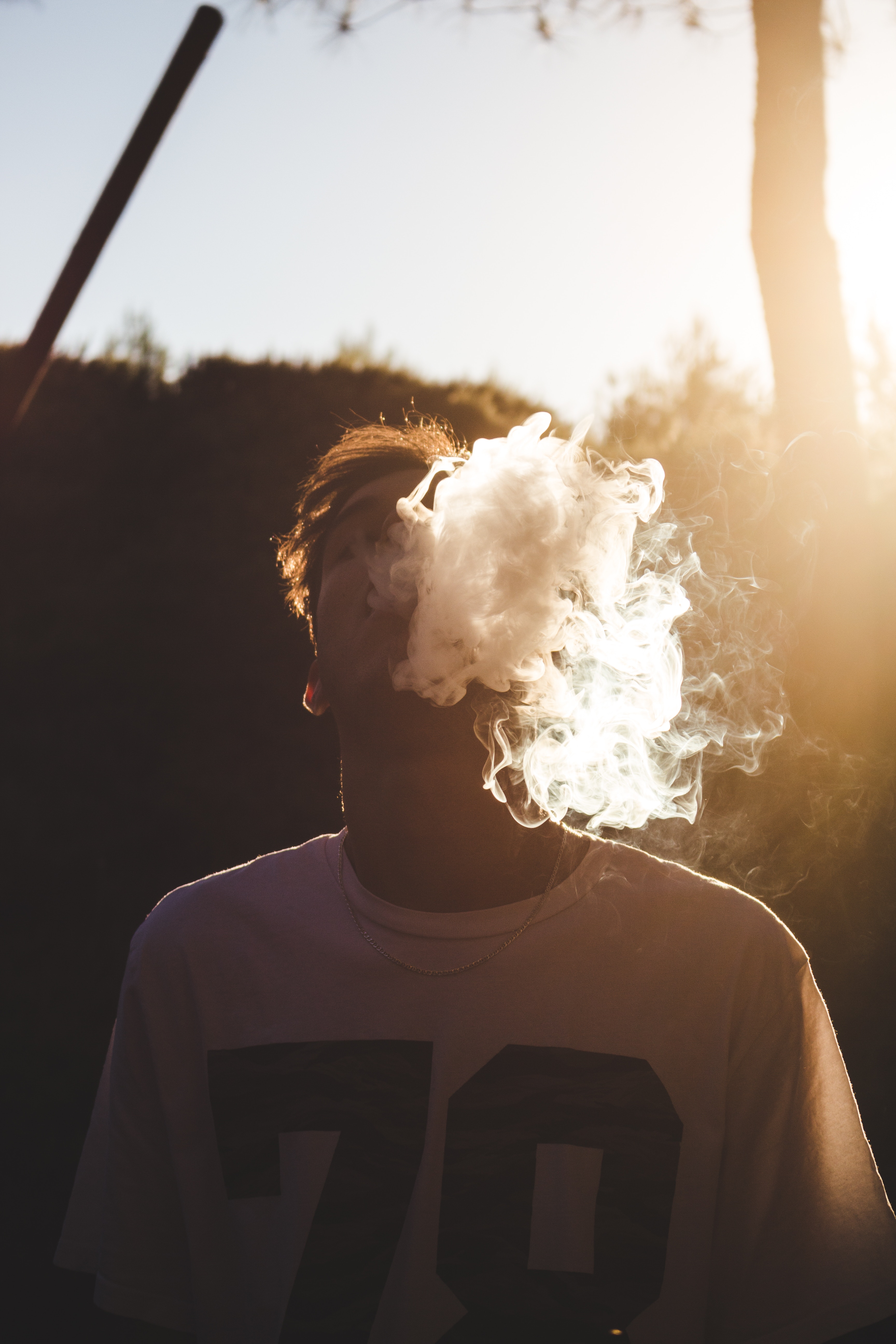 young person blowing smoke into air