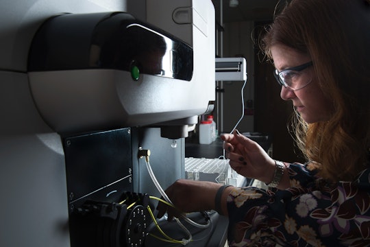 A scientist in a darkly lit lab uses using a microwave plasma atomic emission spectrometer