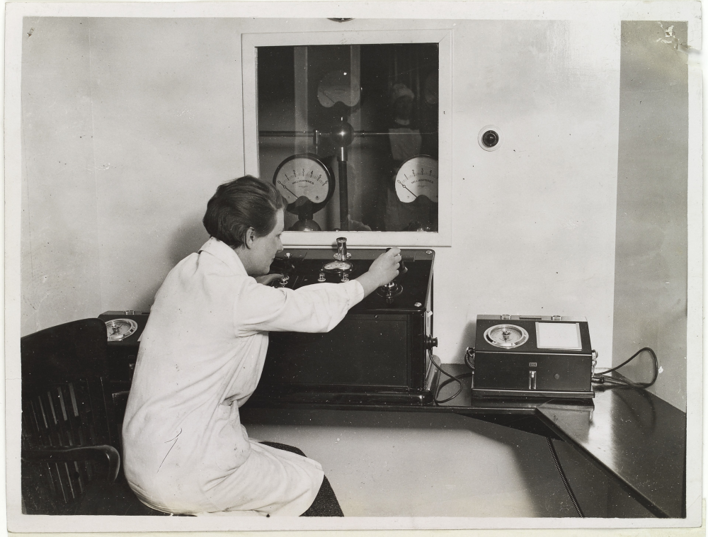 A medical scientist in the 1930s fiddles with an X-ray machine for cancer therapy.