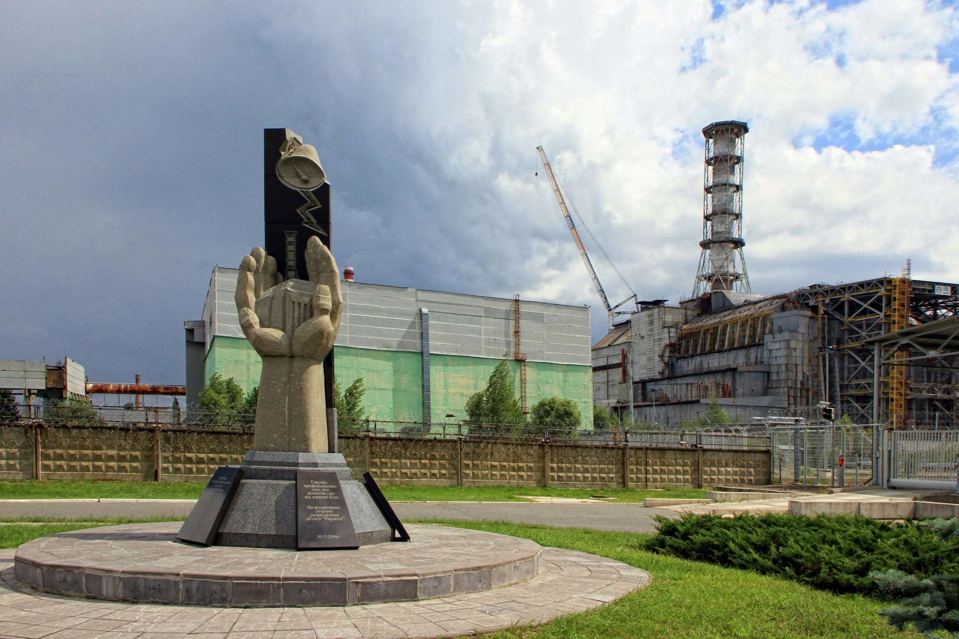 a statue in chernobyl with the wreckage of the plant in the background
