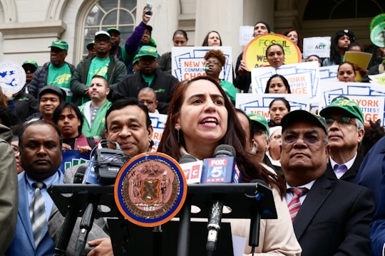 Maritza Silva-Farrell speaks at a podium outside of New York City Hall in front of a crowd of people.