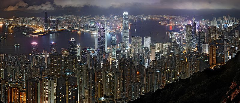 The skyline of Hong Kong, as seen at night. Many tall skyscrapers glow with artificial light.