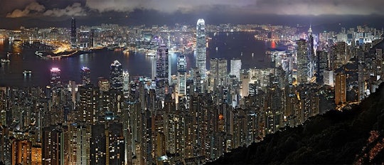 The skyline of Hong Kong, as seen at night. Many tall skyscrapers glow with artificial light.