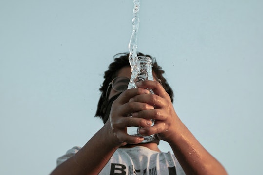 man with water a man spilling water out of a glass jar, photographed from below