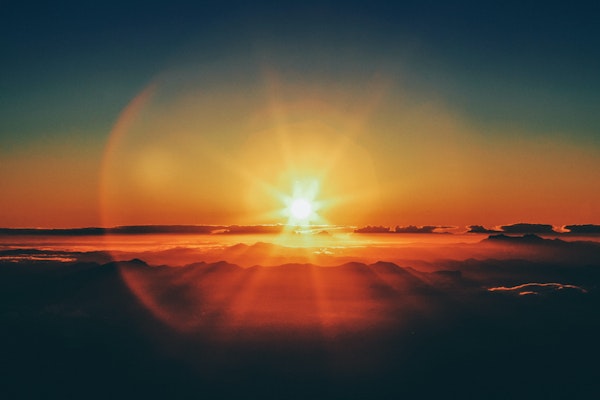 the sun setting and shining against a landscape