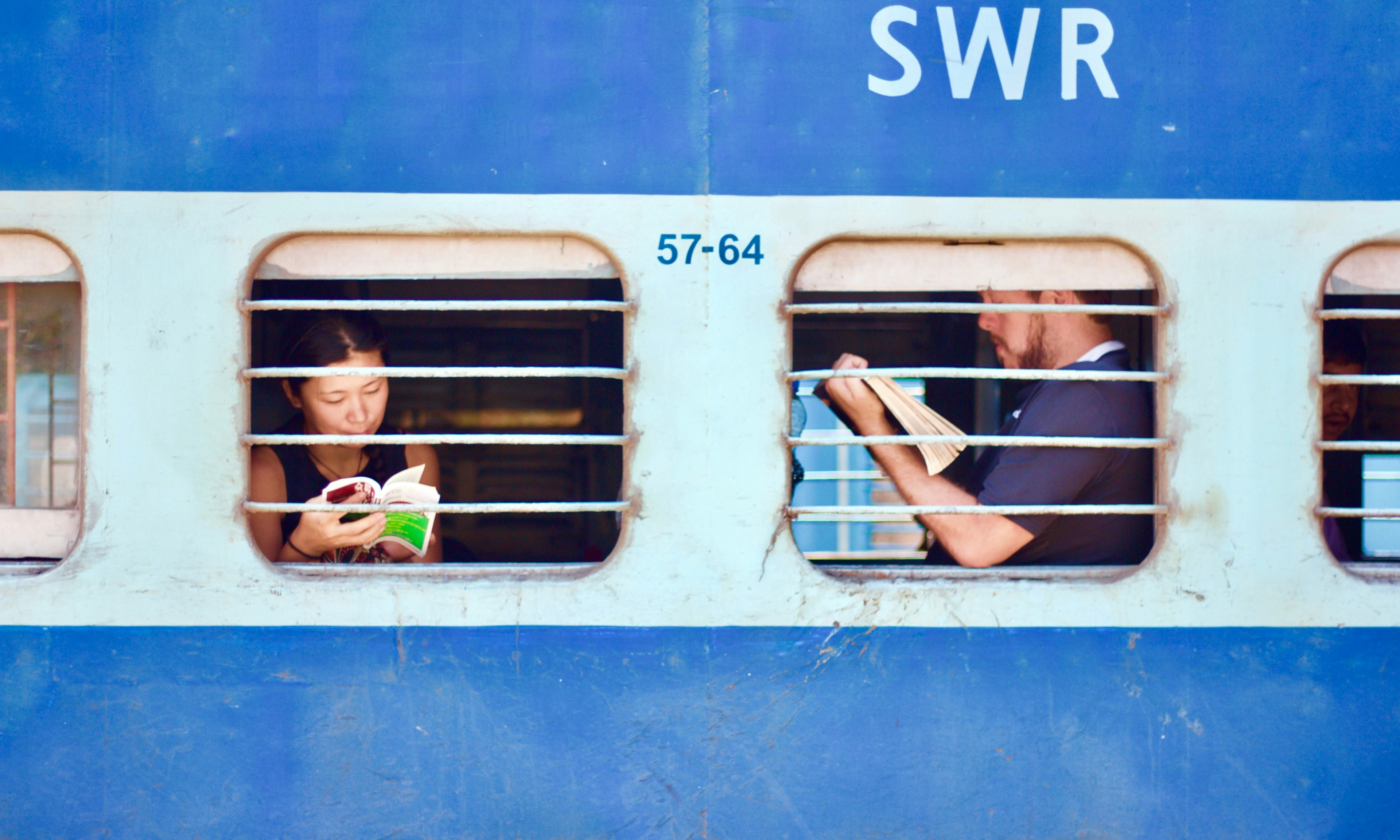 two people through the windows of a blue train