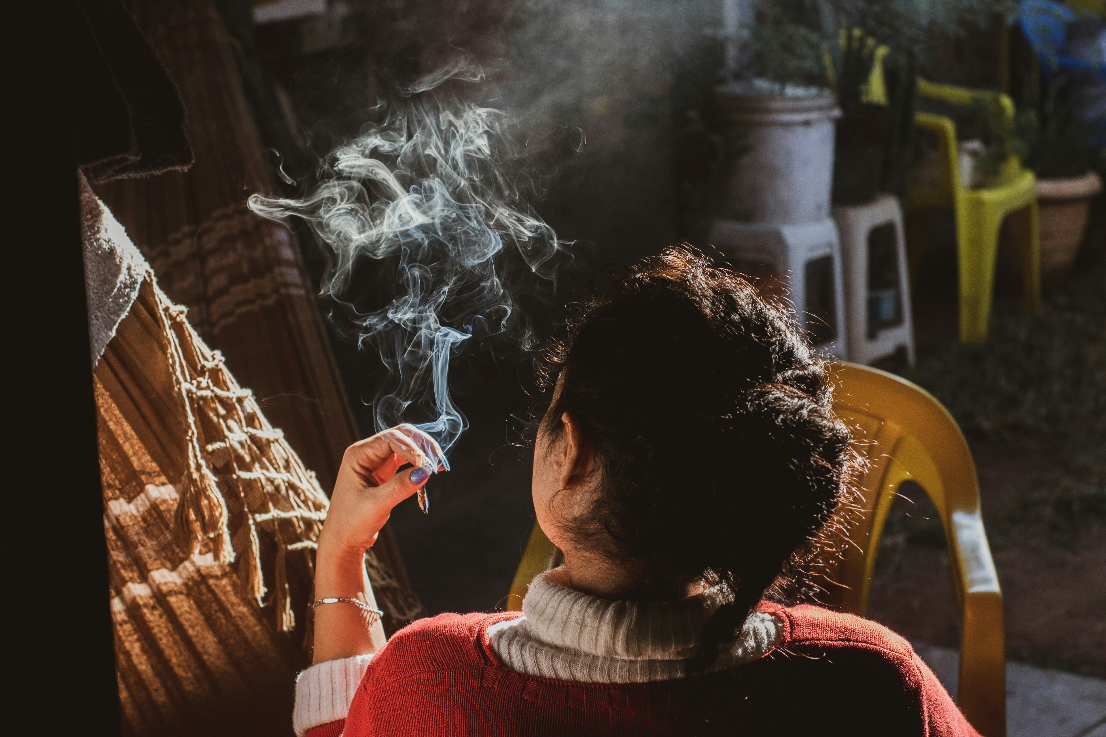 Woman smoking either tobacco or marijuana (weed).