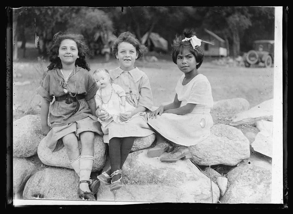 Three campers, 1920, sitting on a stone wall