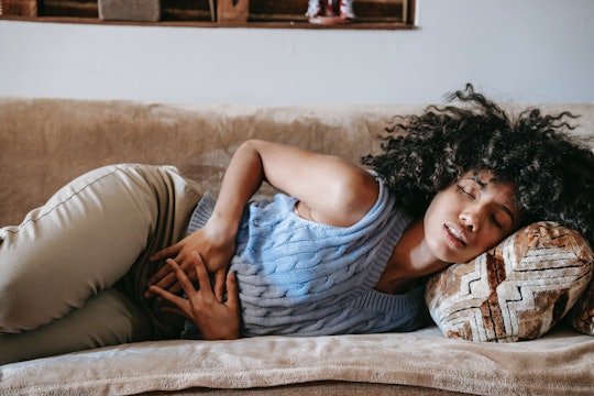 A woman laying on a couch holding her stomach