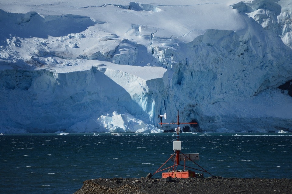 a weather station on a lake with a glacier in the background