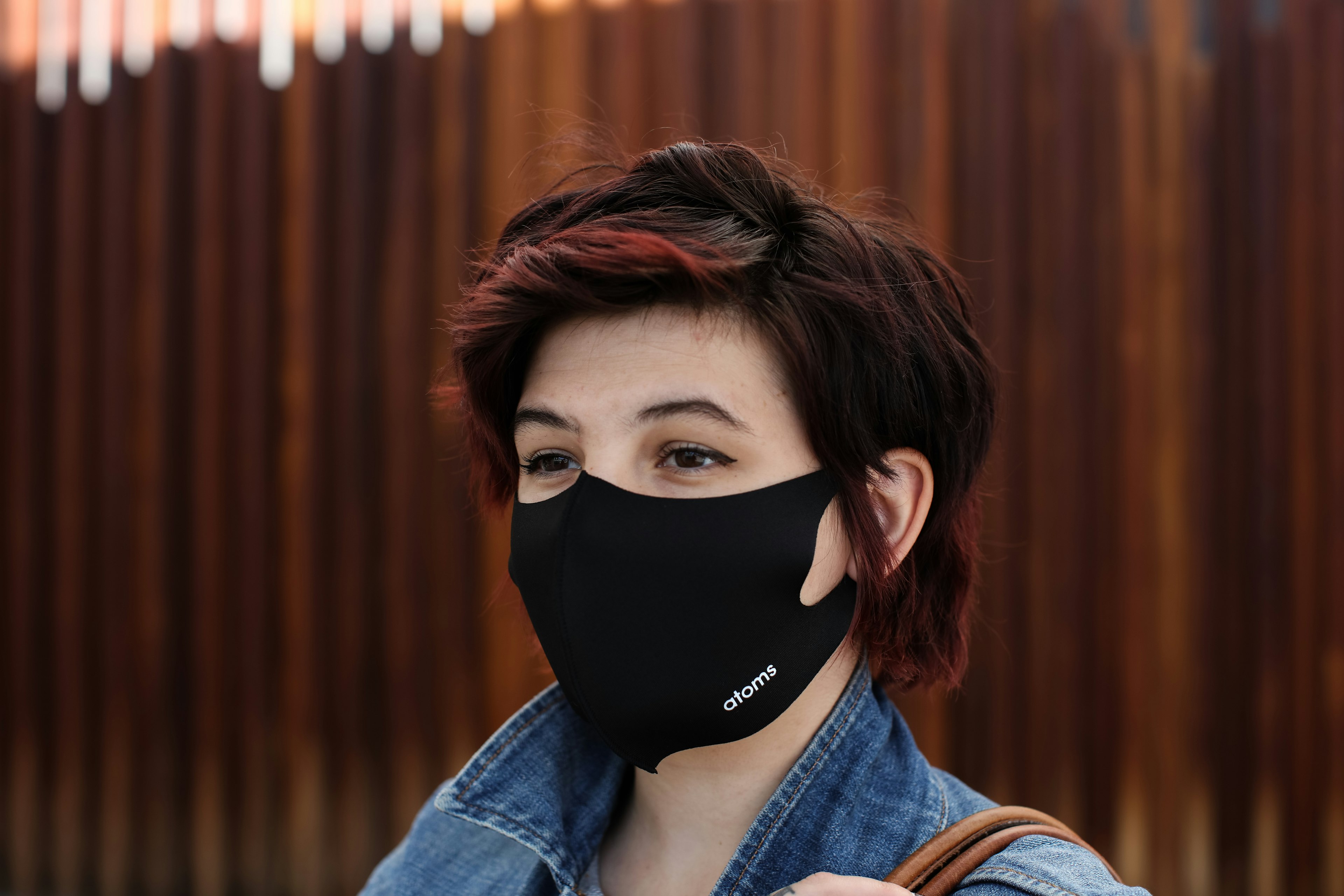 a woman with short hair smiling from behind a black mask