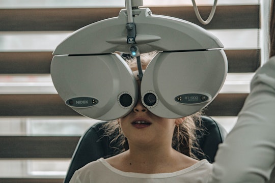 A child's face is covered with equipment for an eye exam.