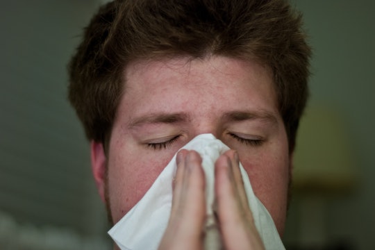 Man sneezing into a tissue Man sneezing into a tissue