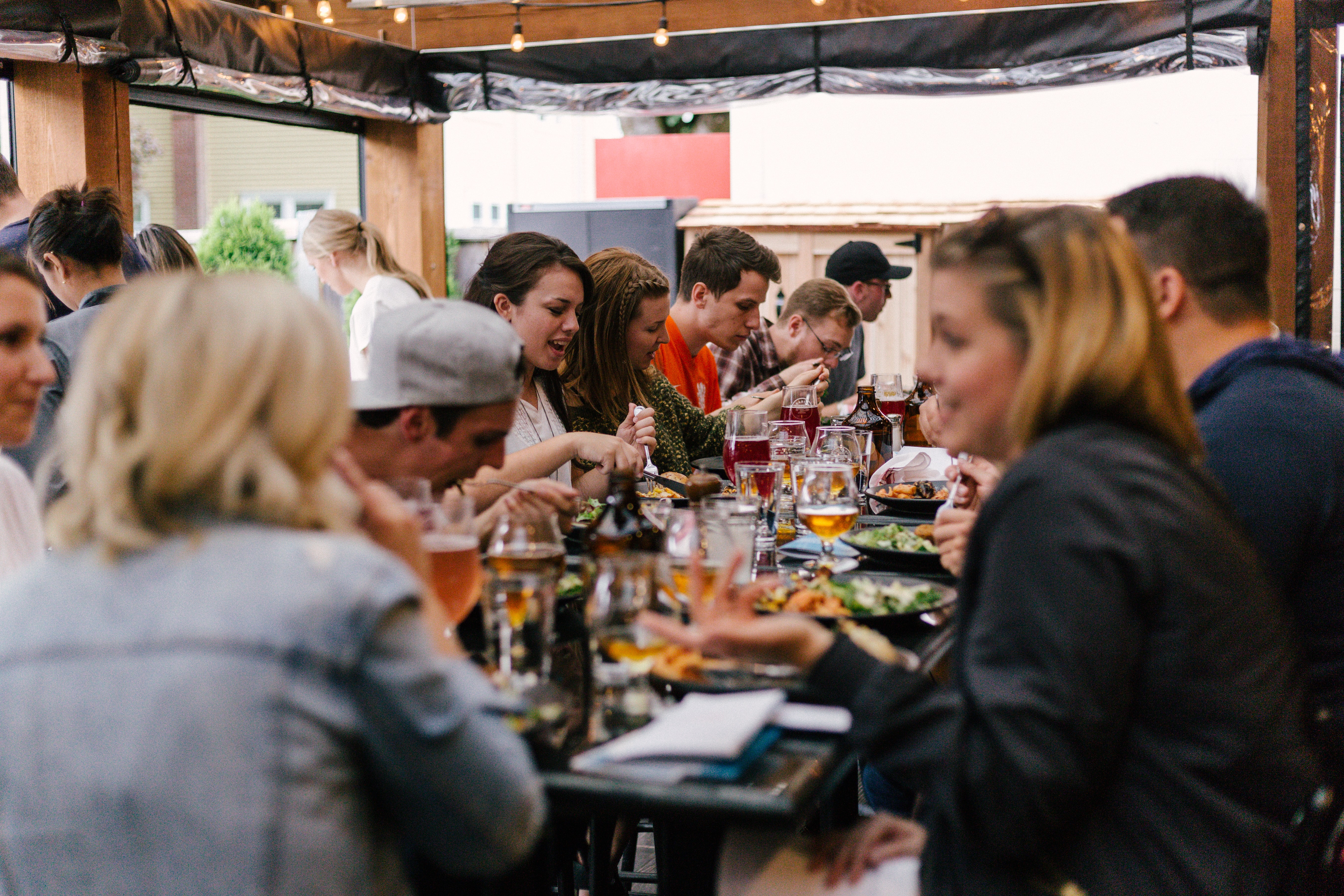 A large group of people sitting at a long table eating at a restaurant.