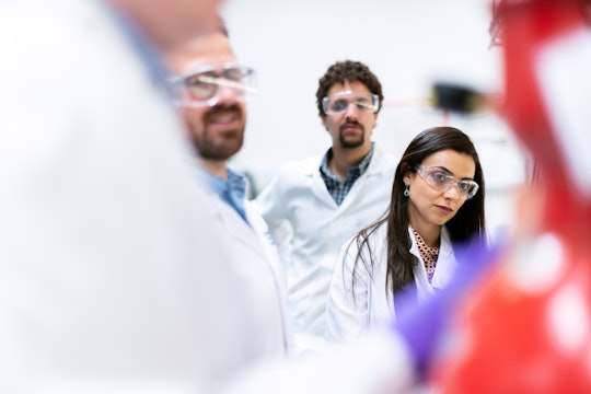 A group of scientists and engineers watches a procedure in a laboratory