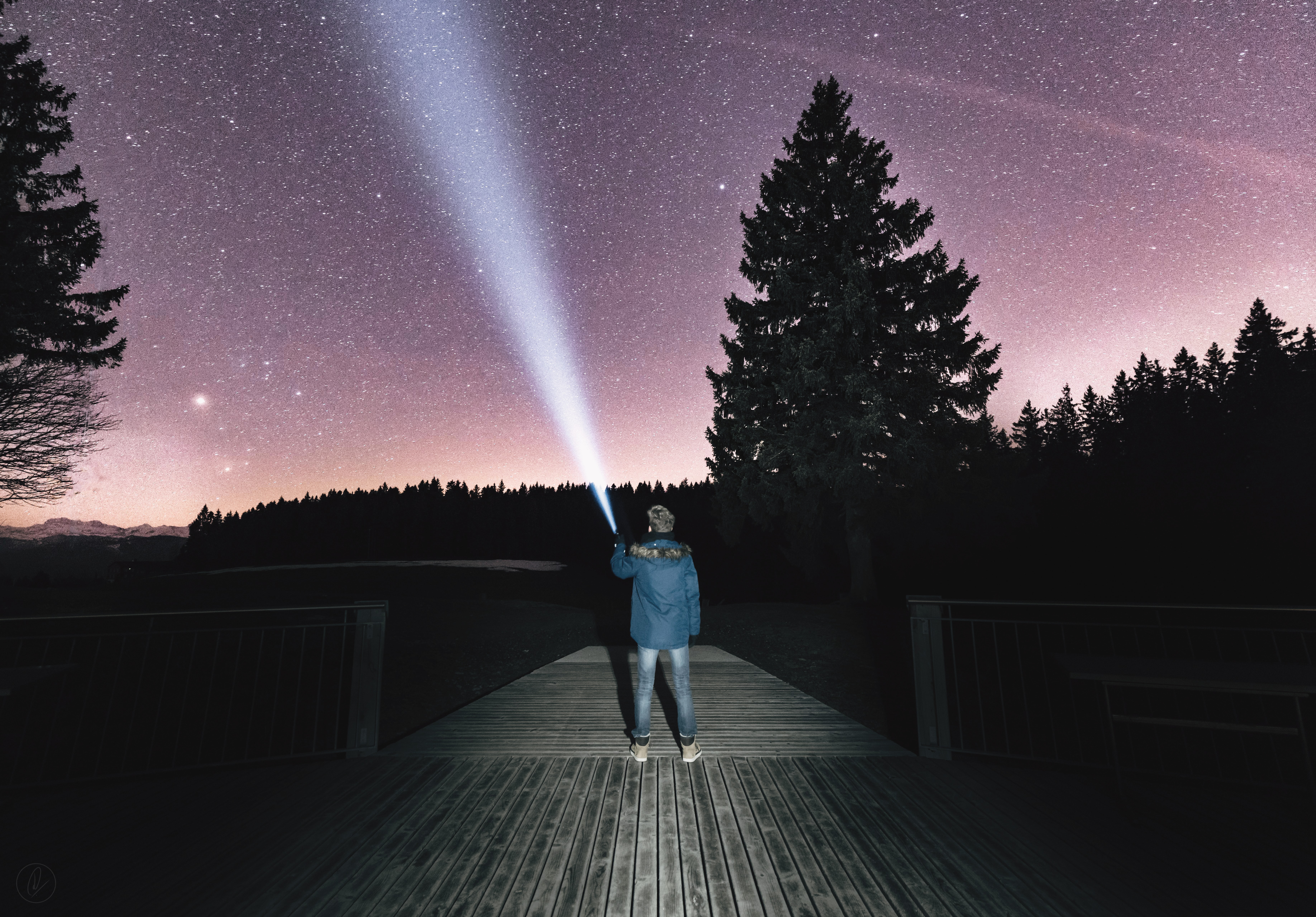 person holding flashlight aiming at dusky sky