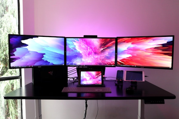 four lcd screens arranged on a desk with a bright pink and blue design on the screens