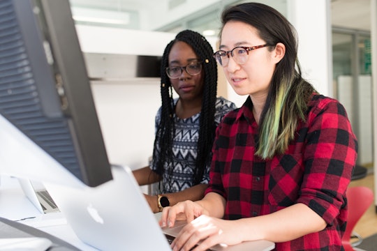 Two women working together on a computer. Two women working together on a computer.