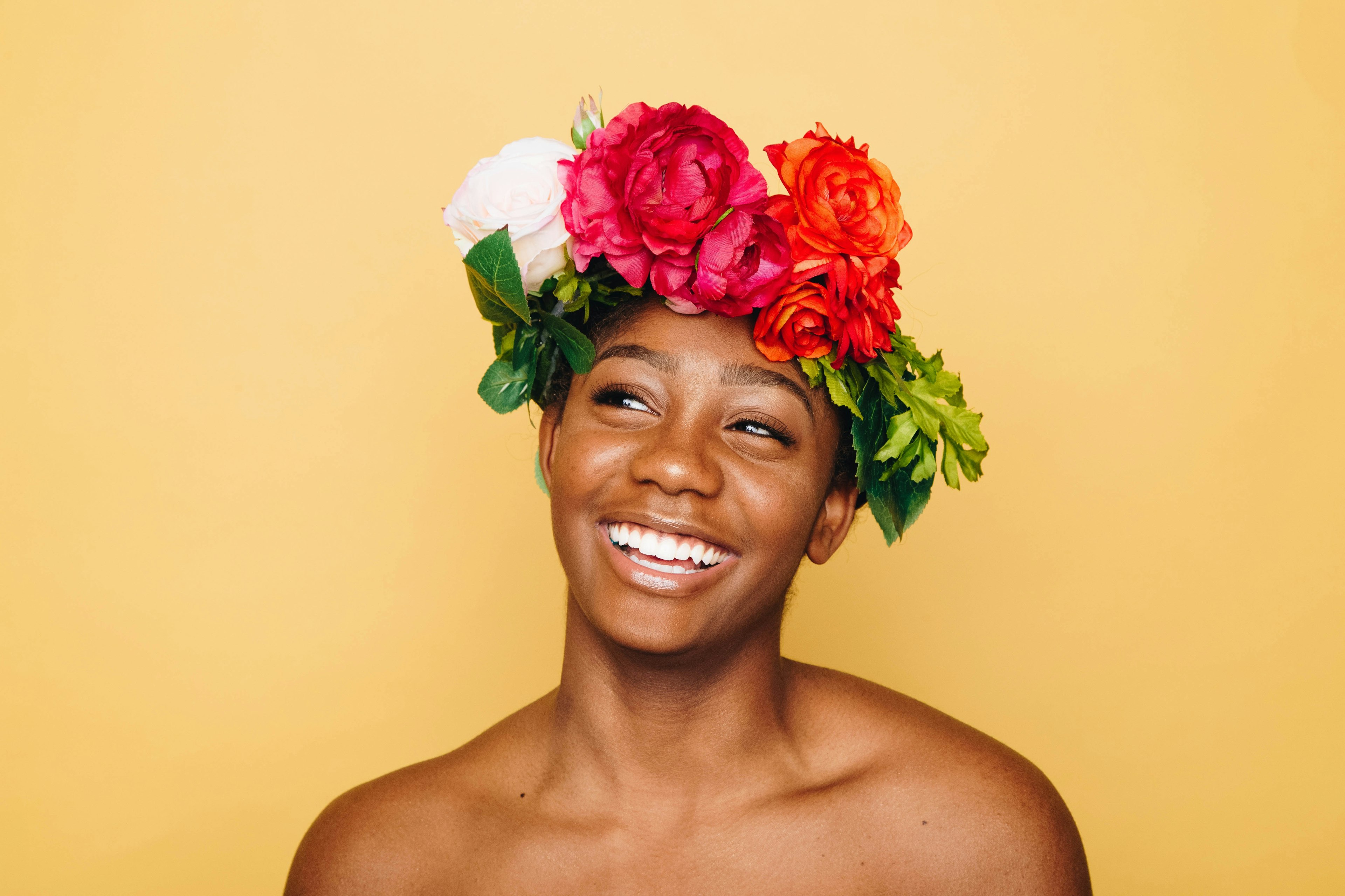 A smiling woman wearing a headdress made of flowers.