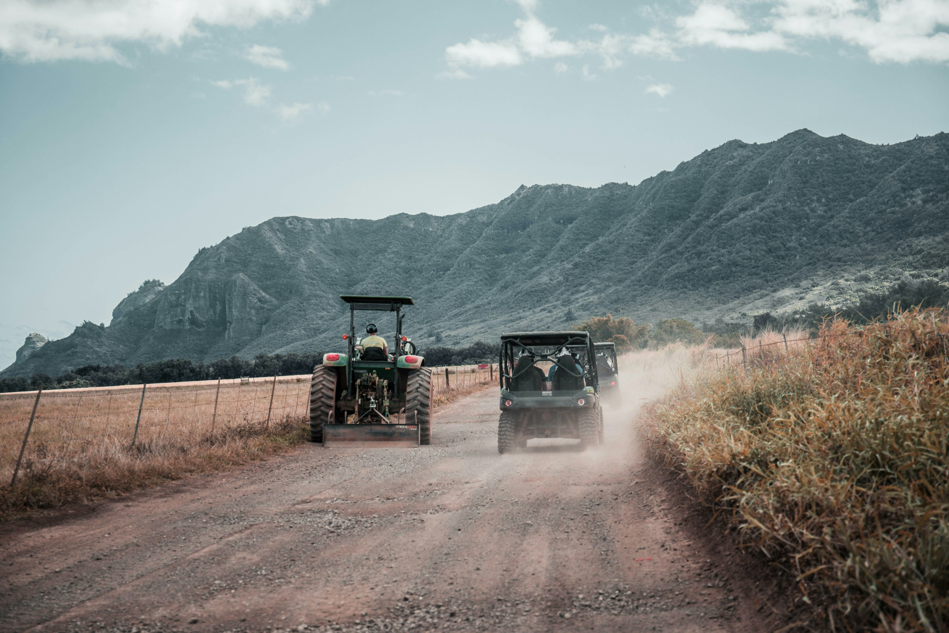 two tractors drive down a very dusty road