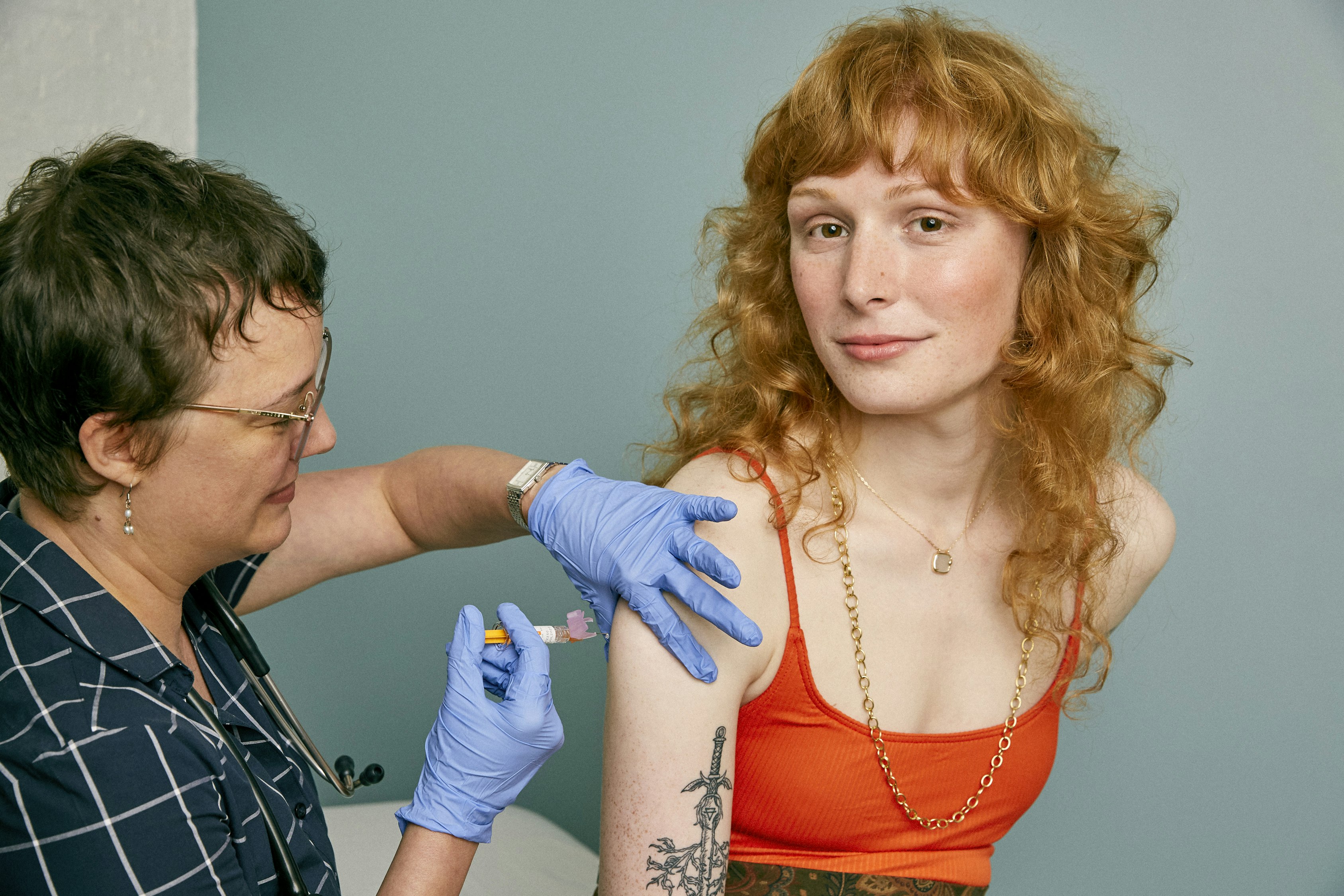 A woman with long red hair receiving a vaccination shot