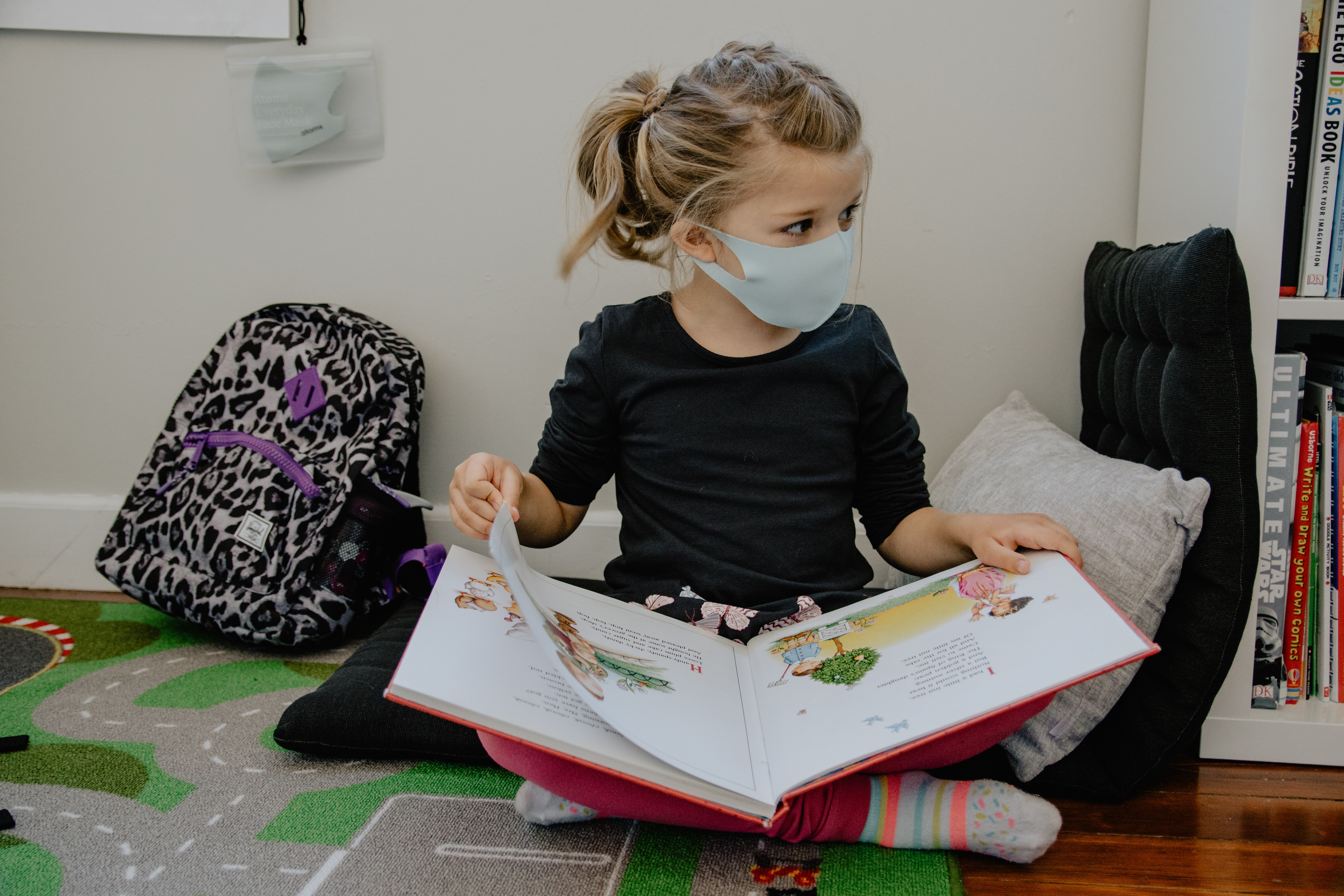 a girl reading a book while wearing a mask