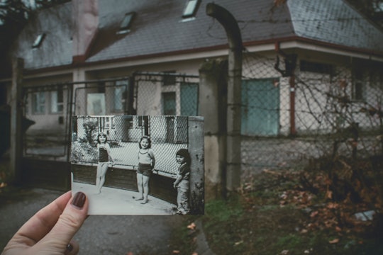 an old black-and-white photograph of three small children being held up against the place they were standing in the modern day.