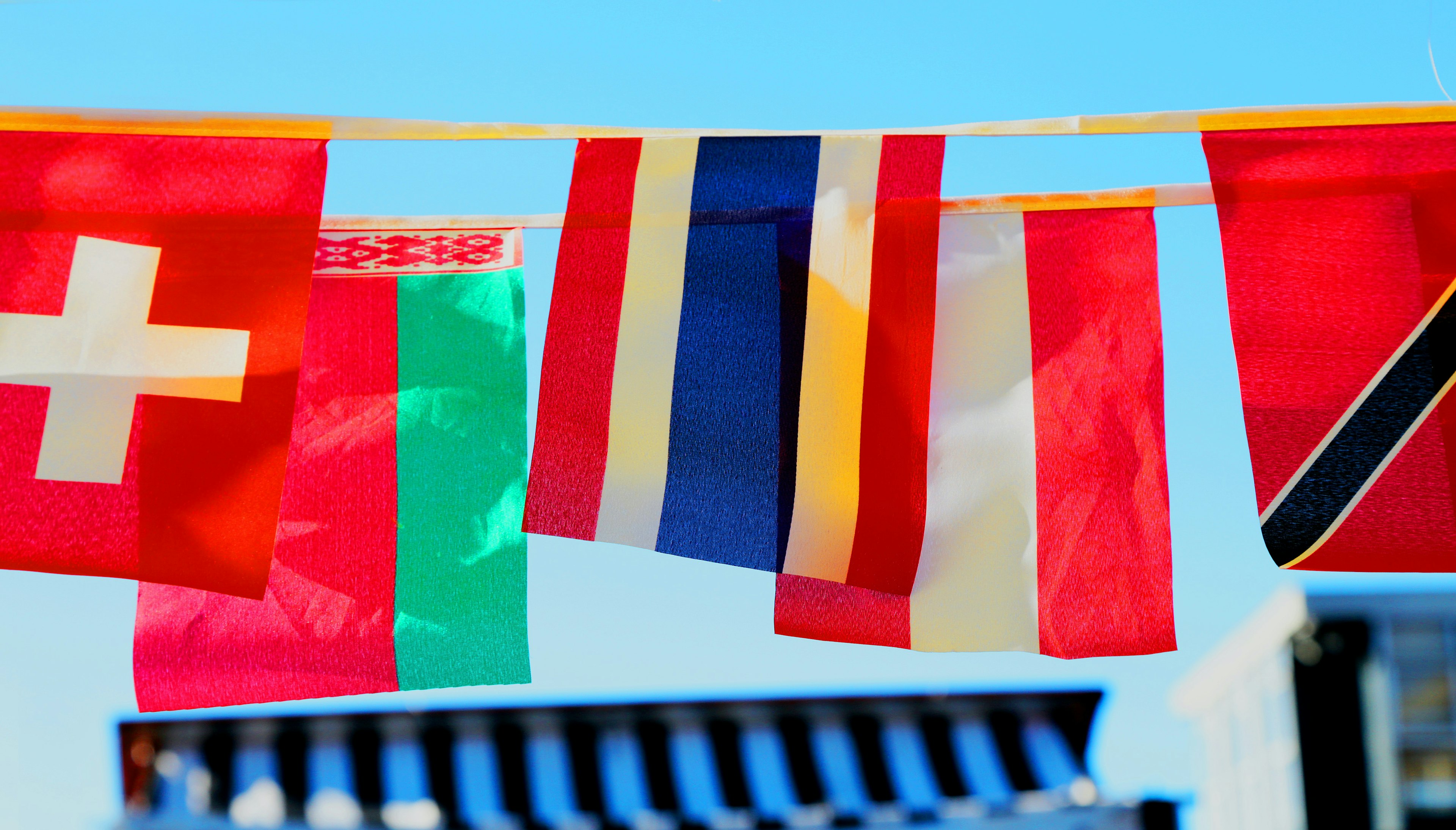 six different countries' flags hanging against a blue sky