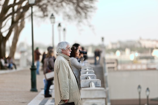 A man with gray hair and a gray mustache looking over a railing
