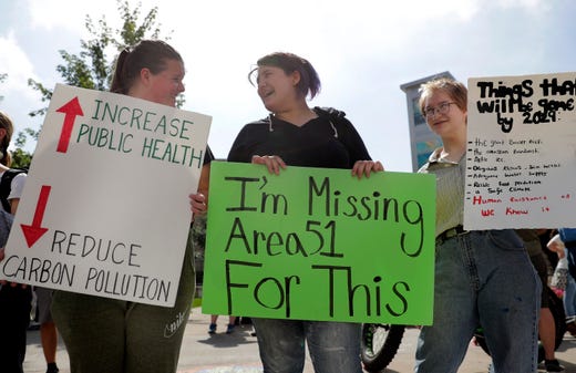 Climate strikers in Appleton, WI, USA, holding signs, one of which reads "I'm missing Area 51 for this."
