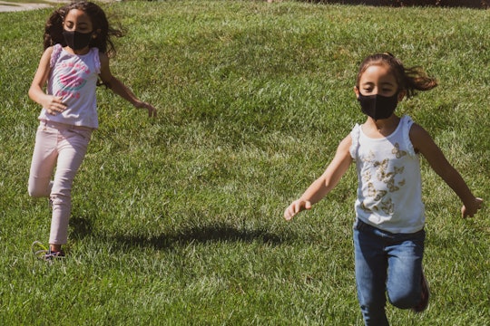 two girls wearing masks running outside