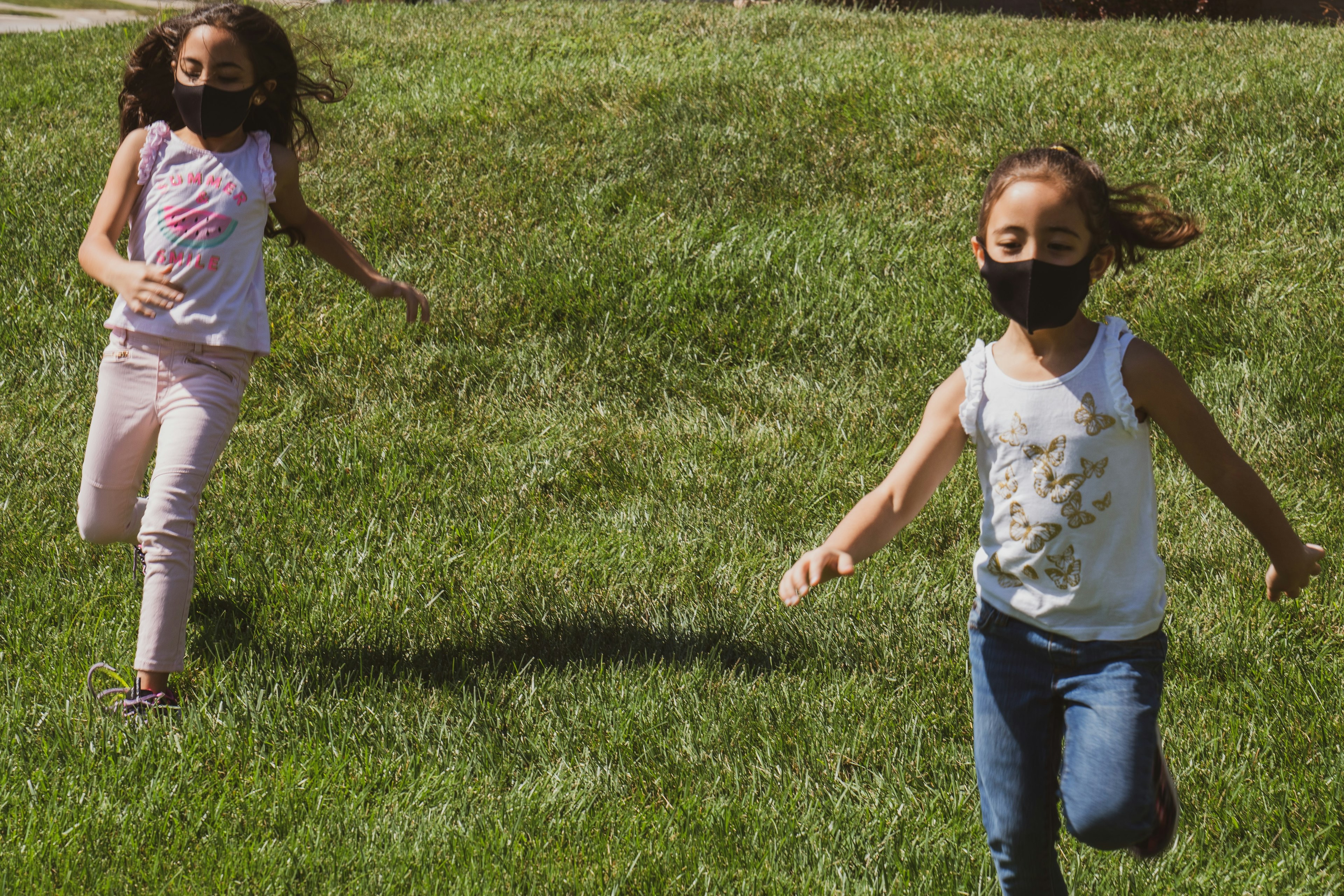 two girls wearing masks running outside