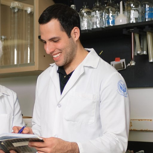 Juan Ruiz in a lab with notebook and writing in a lab book