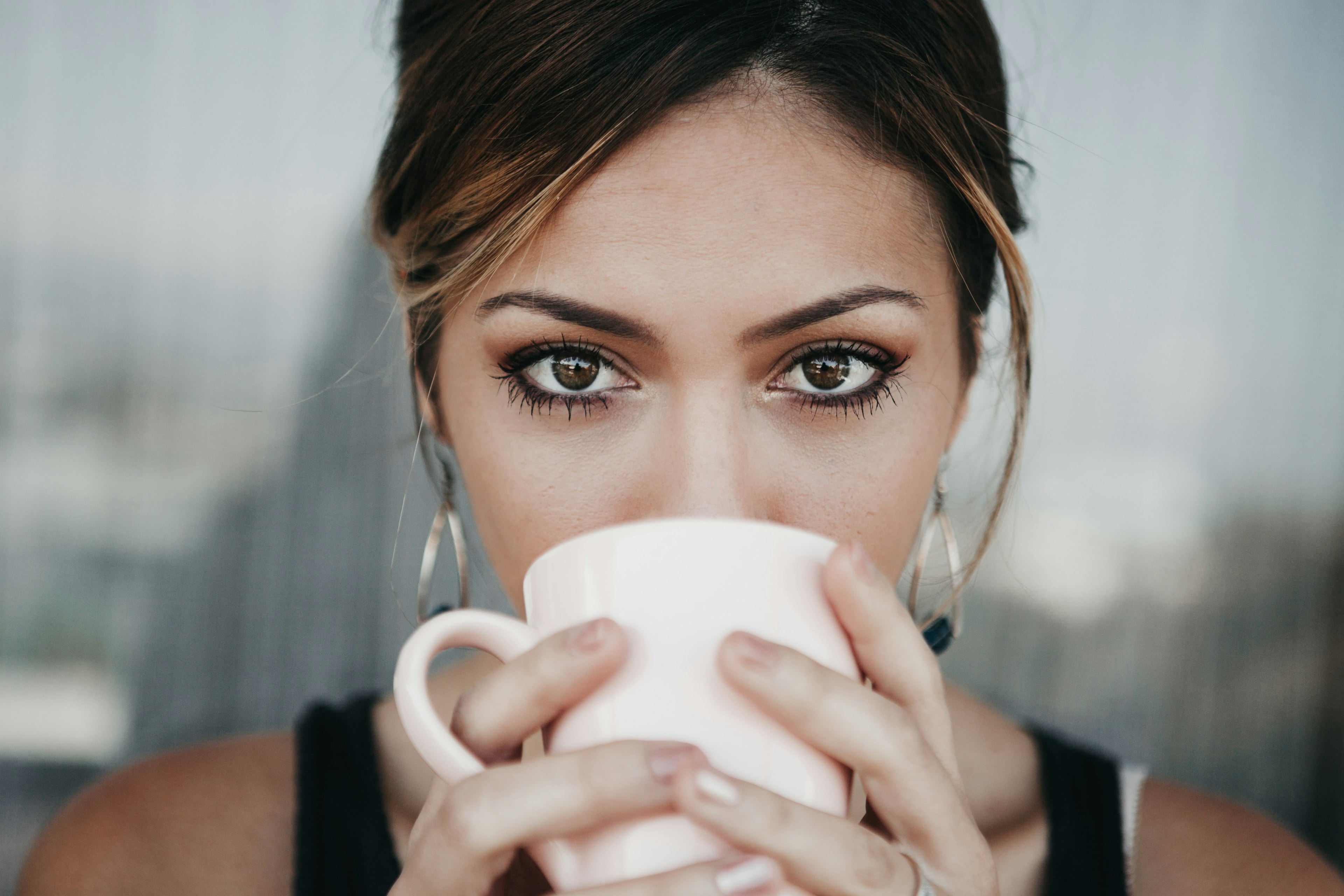 a woman drinking coffee and looking at the camera