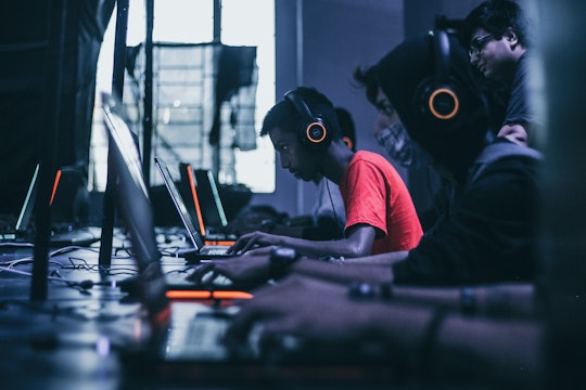 People playing video games on their laptops, looking very intense.