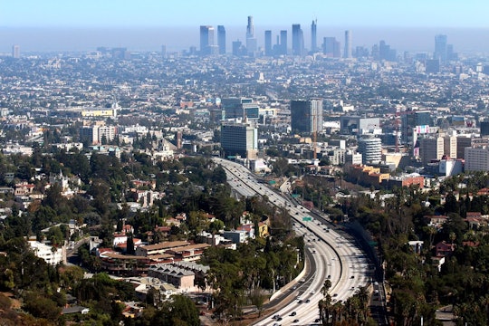 a shot of a freeway into a big city, with hazy air pollution in the distance
