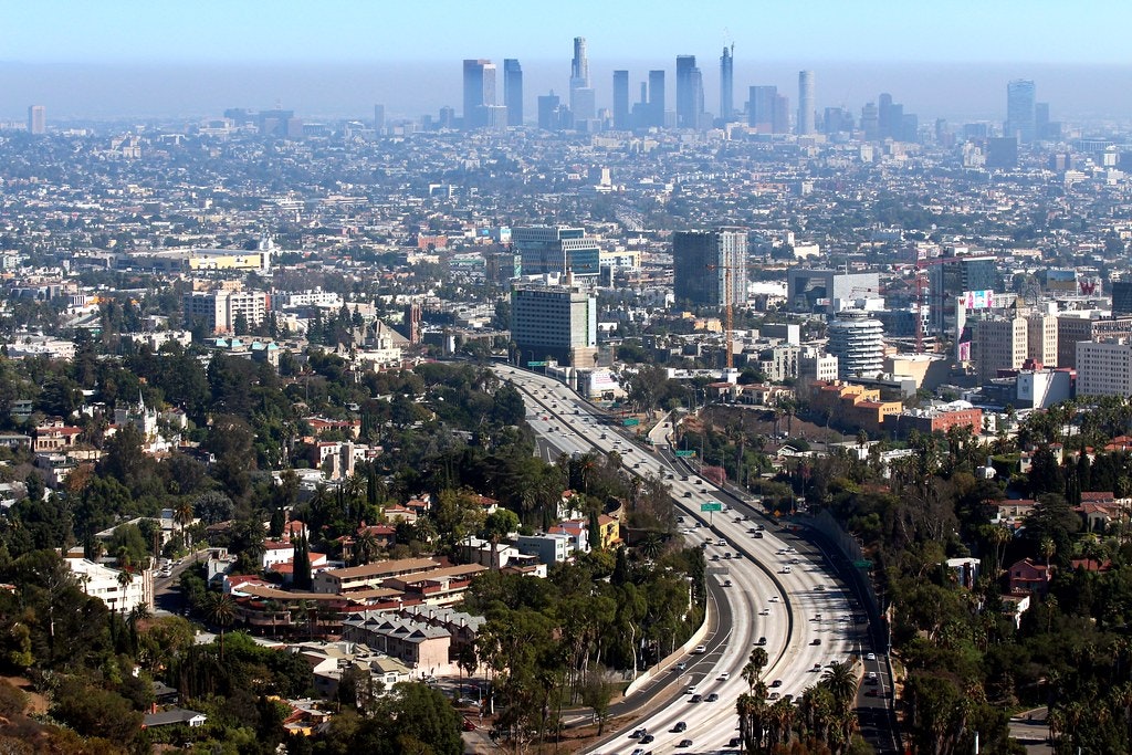 a shot of a freeway into a big city, with hazy air pollution in the distance