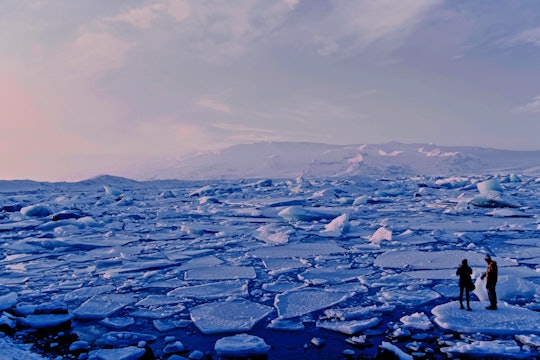 arctic warming and people two people standing on a sea of cracked ice