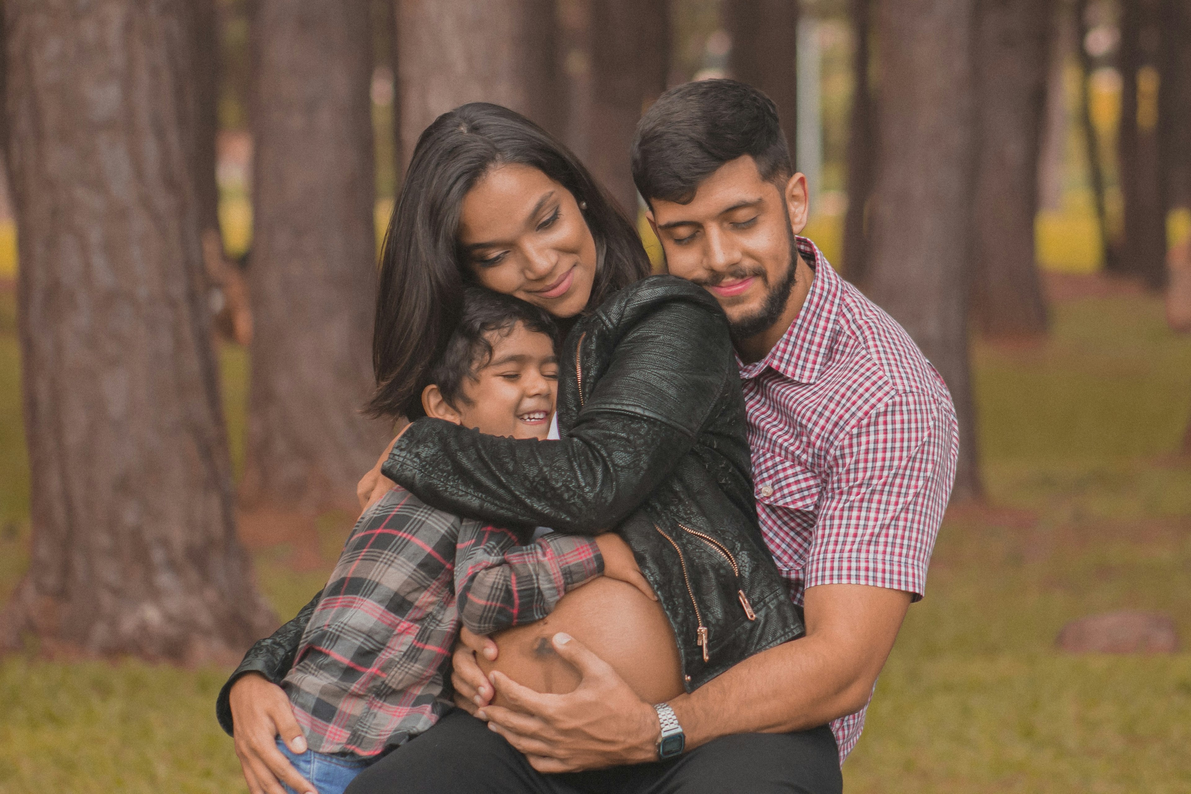 a pregnant woman hugging a man and child