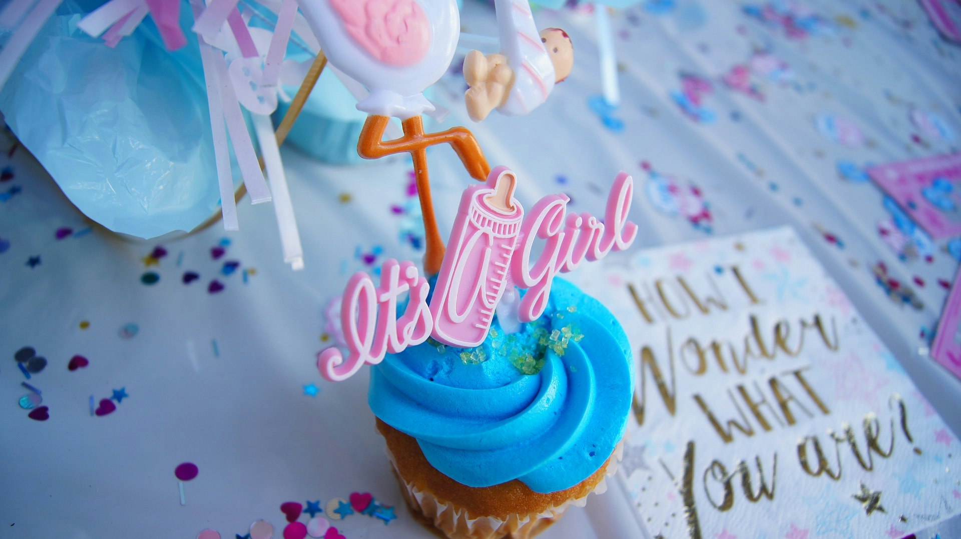 Gender reveal cupcake with blue icing and a pink "it's a girl" decoration