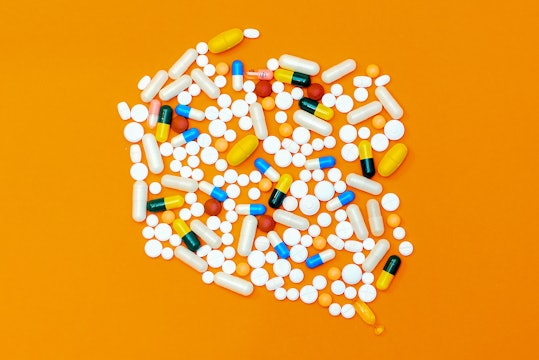 a pile of white and colored pills against a bright orange background