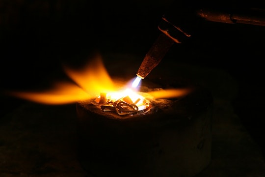 melting a welder using a torch to melt metal