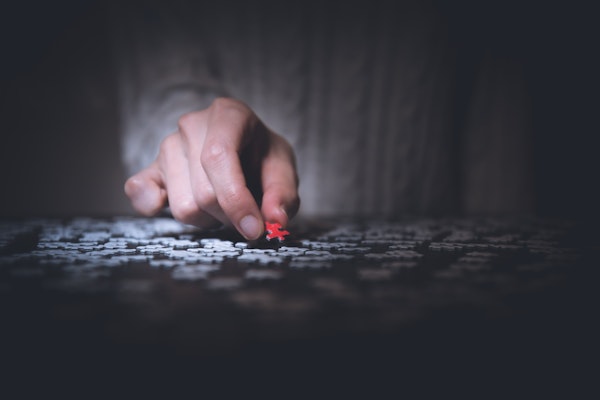 a hand picking up a red puzzle piece