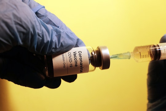 A syringe pulling from a vial labeled "coronavirus vaccine, COVID-19"