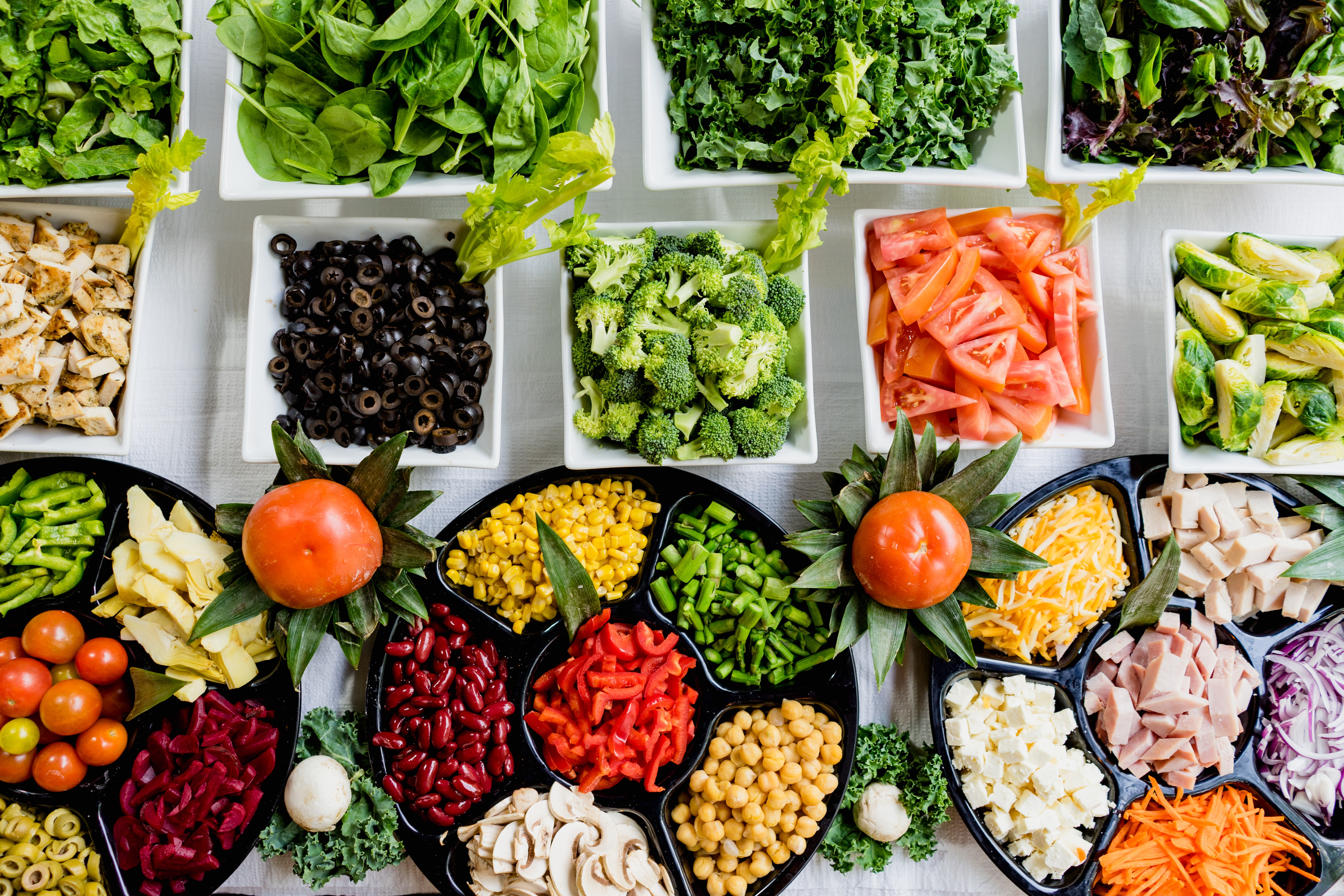 food bowls of vegetables, meat, cheese on a table