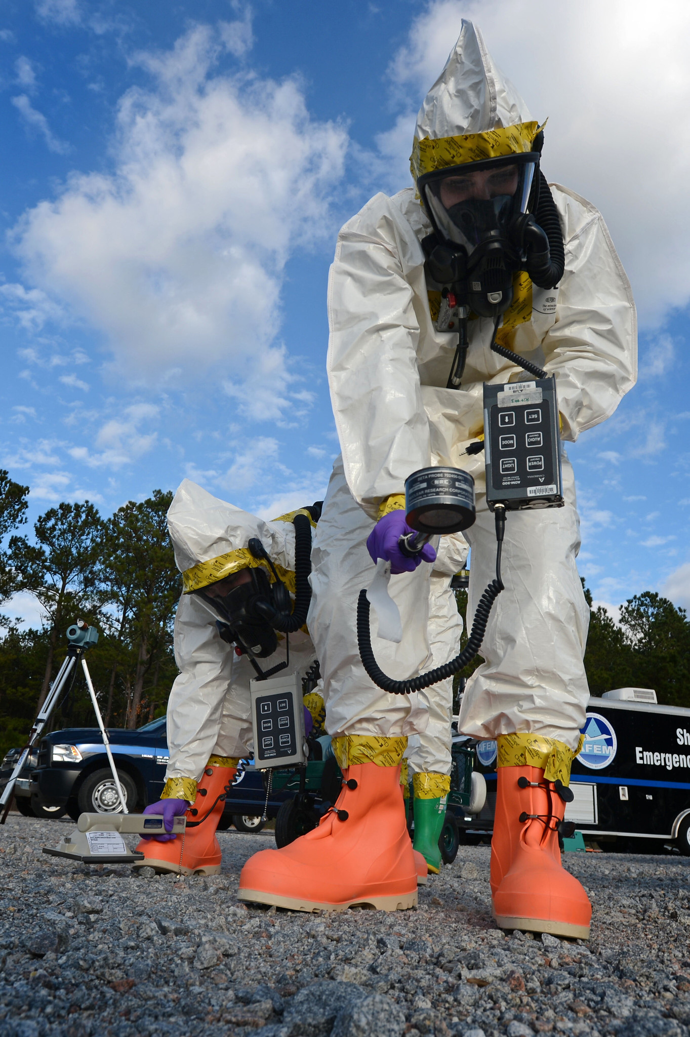 two people wearing PPE and using a meter