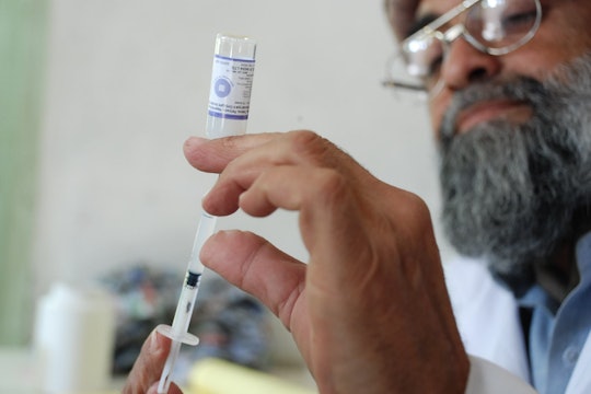 A doctor pulls a dose of vaccine from a vial